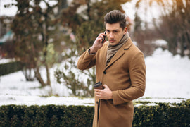 young man coat outside talking phone drinking coffee